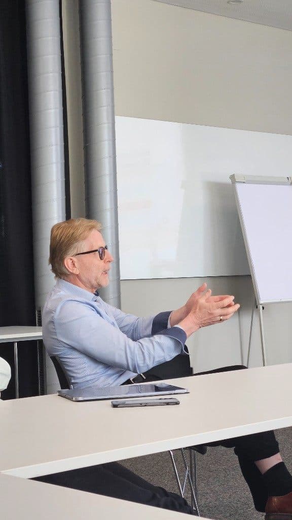 Michael Defranceschi erklärt am Tisch mit ausdrucksstarken Gesten seinen Ansatz zum VibeCoding.