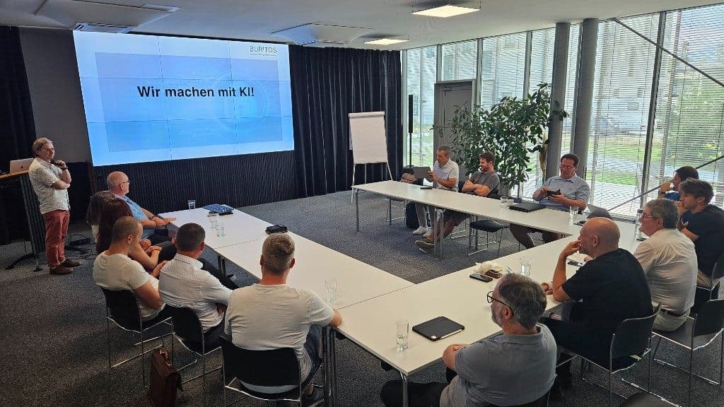 Blick über die Teilnehmenden auf Gerhard Burtschers Vortrag und die große Leinwand im GlessHub.