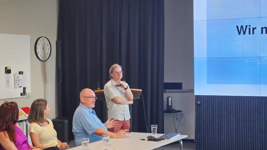 Gerhard Burtscher im Dialog mit Teilnehmenden vor der Präsentationsleinwand.