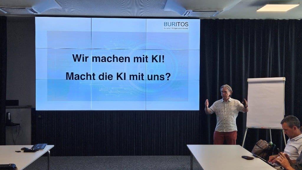 Gerhard Burtscher vor der Folie „Wir machen mit KI! Macht die KI mit uns?“.